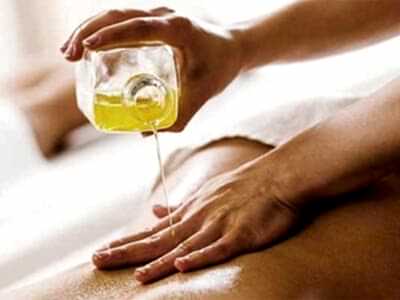 aromatherapy oil being poured onto a woman’s back