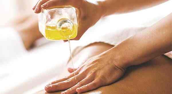 aromatherapy oil being poured onto a woman’s back