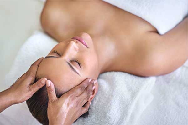 therapist applying pressure to a woman's head, during an Indian head massage