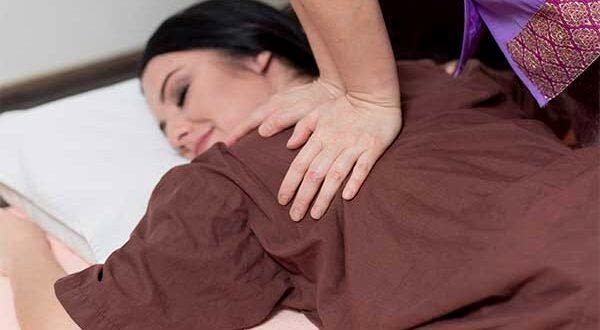 therapist applying Thai massage techniques to a woman's shoulders